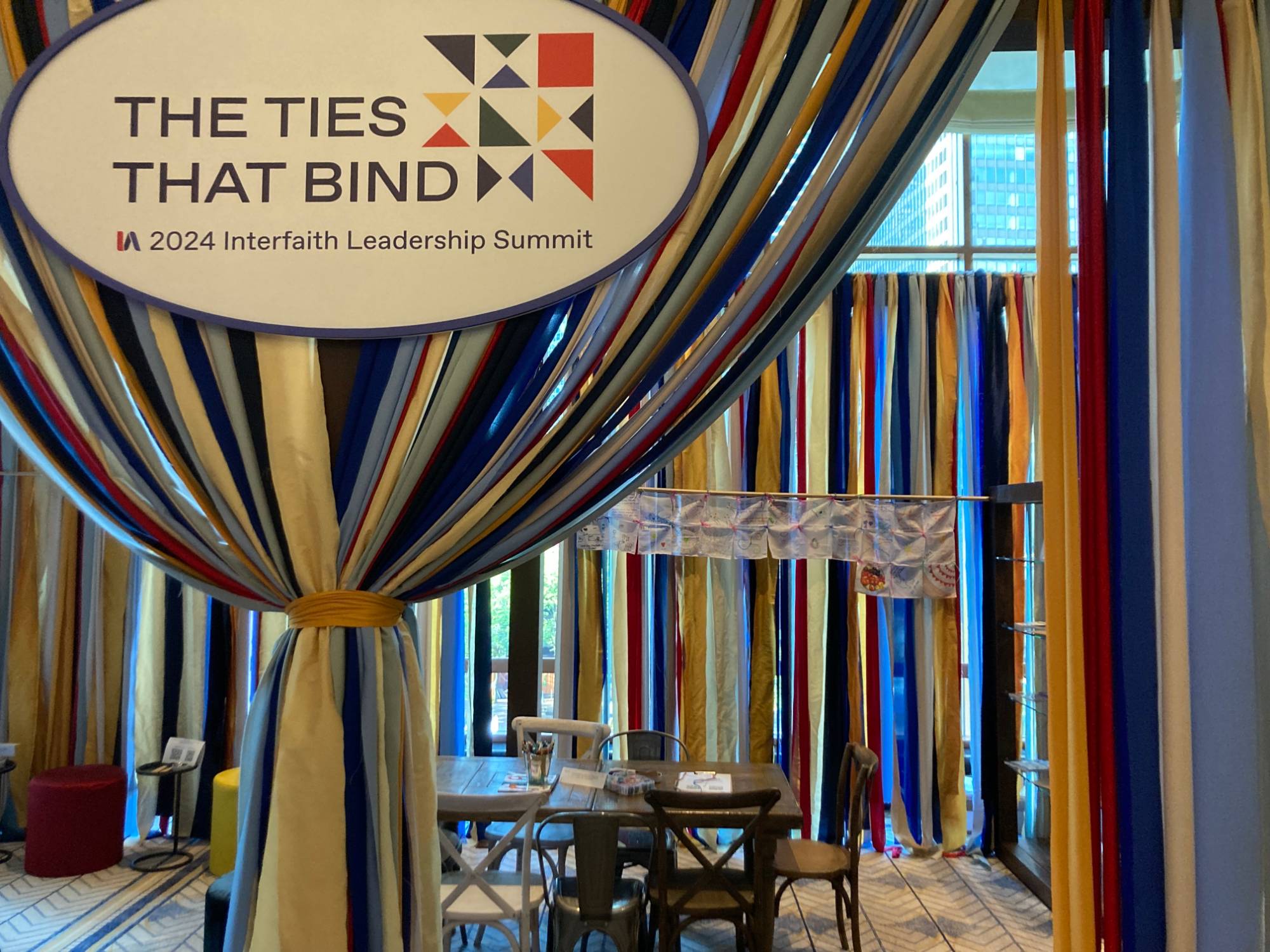 A banner with Ties That Bind on it, the theme for Interfaith Americas Summit for 2024  written on it.